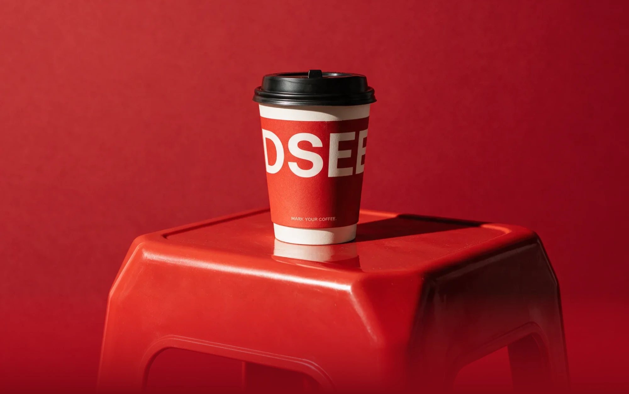 Vaso de café DSEE sobre un taburete rojo